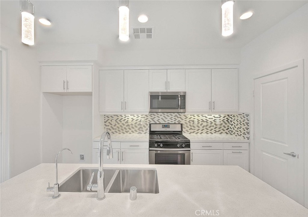 11411 VuePointe Way, Unit E El Monte, CA 91732 - Photo 12 of 38 a kitchen with white cabinets and stainless steel appliances