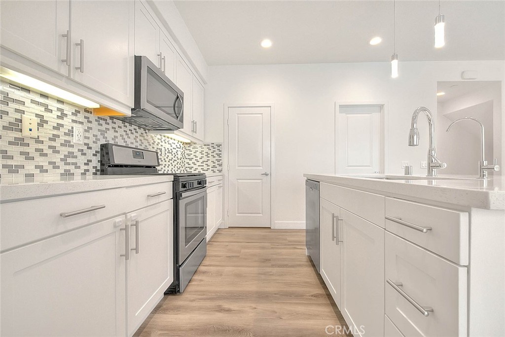 11411 VuePointe Way, Unit E El Monte, CA 91732 - Photo 14 of 38 a kitchen with stainless steel appliances kitchen island granite countertop white cabinets and window
