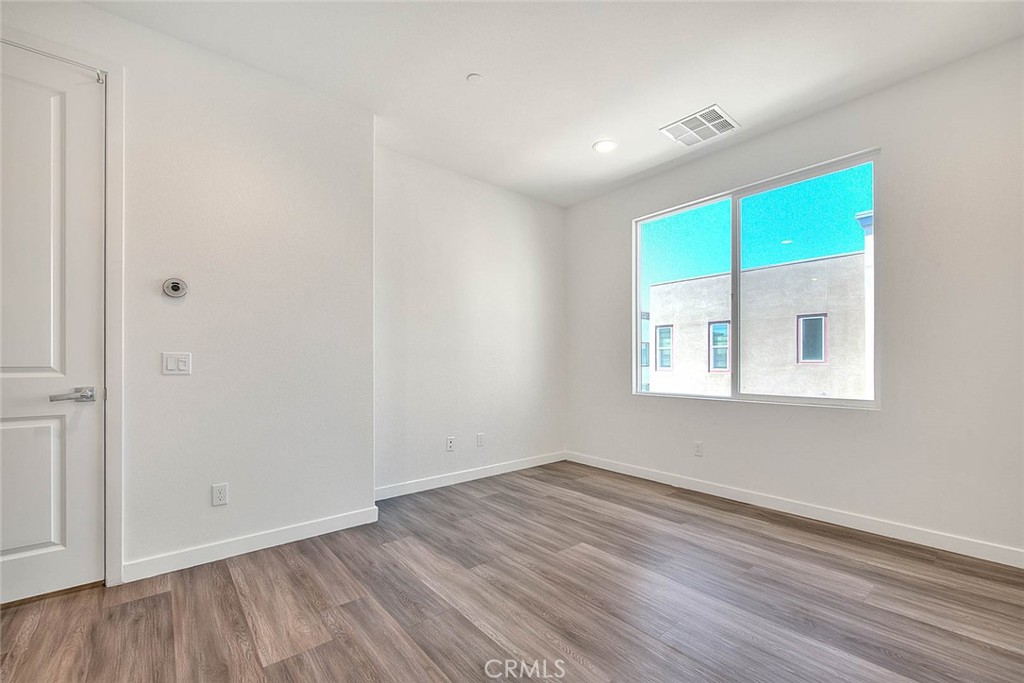 11411 VuePointe Way, Unit E El Monte, CA 91732 - Photo 28 of 38 a view of an empty room with wooden floor and a window