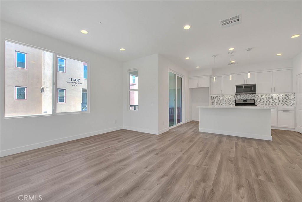 11411 VuePointe Way, Unit E El Monte, CA 91732 - Photo 9 of 38 a view of kitchen with kitchen island granite countertop cabinets and wooden floor