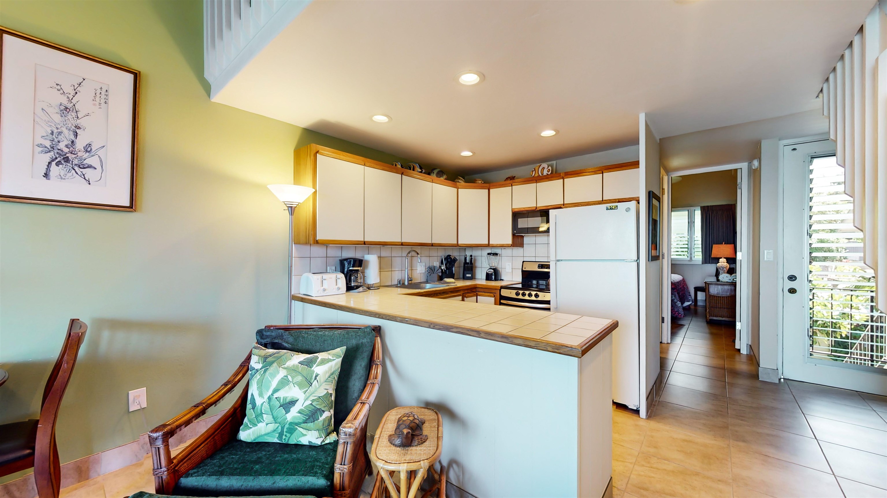 5255 Lower Honoapiilani Road, Unit 219 Lahaina, HI 96761 - Photo 3 of 12 a kitchen with a refrigerator a stove top oven a sink and a dining table with wooden floor