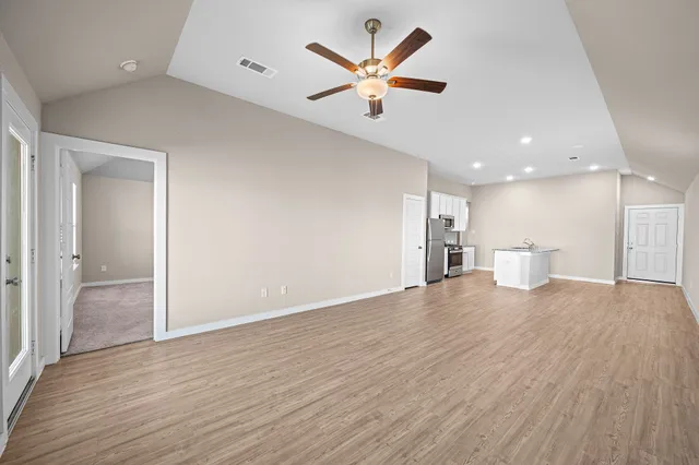 a view of an empty room with a window and wooden floor