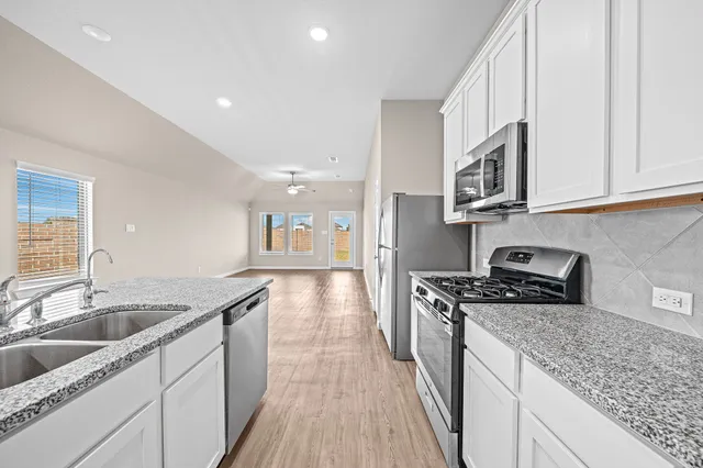a kitchen with stainless steel appliances granite countertop a sink stove and cabinets