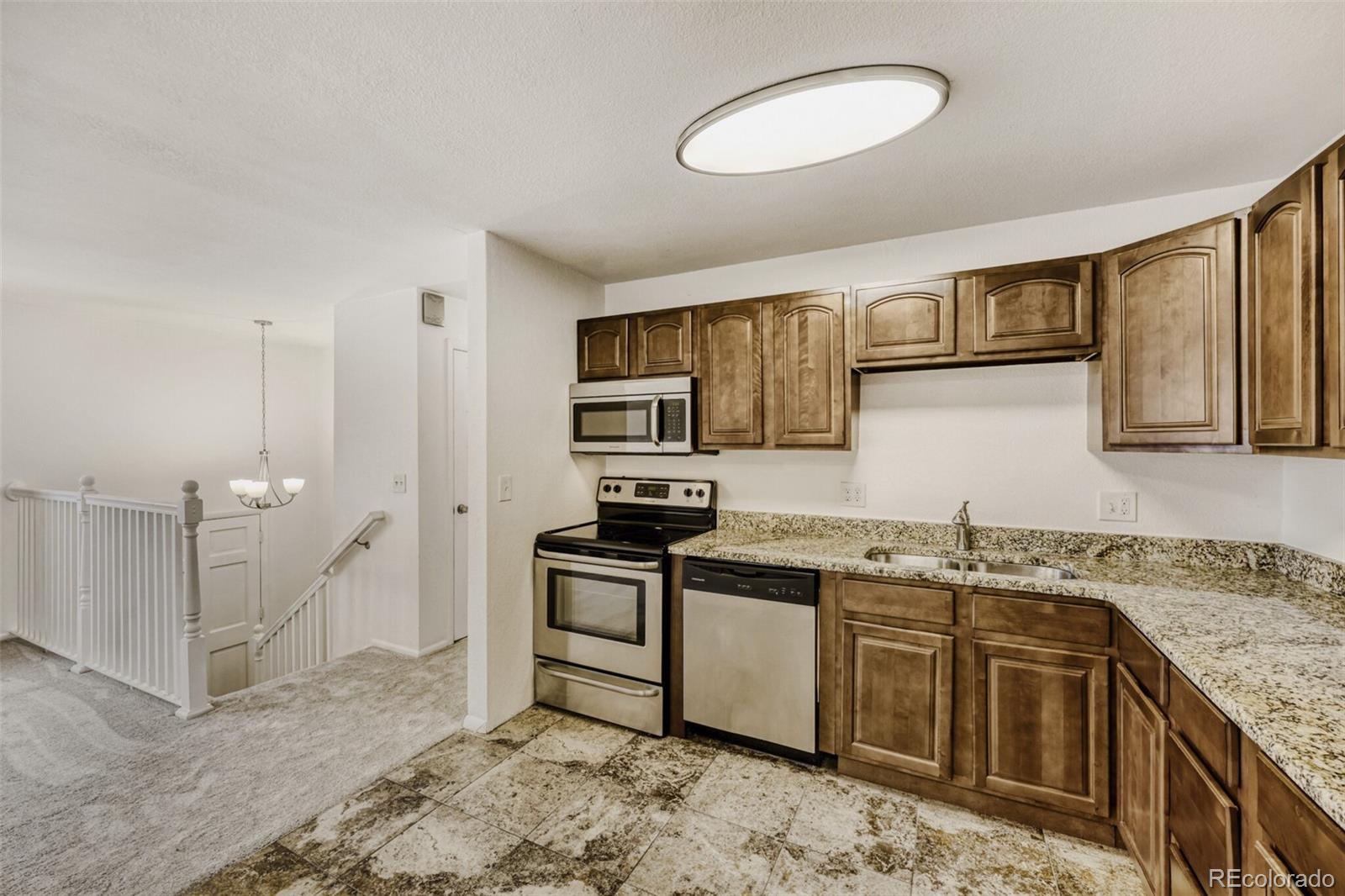 9168 Flower Court Westminster, CO 80021 - Photo 11 of 38 a kitchen with stainless steel appliances granite countertop a sink stove and refrigerator