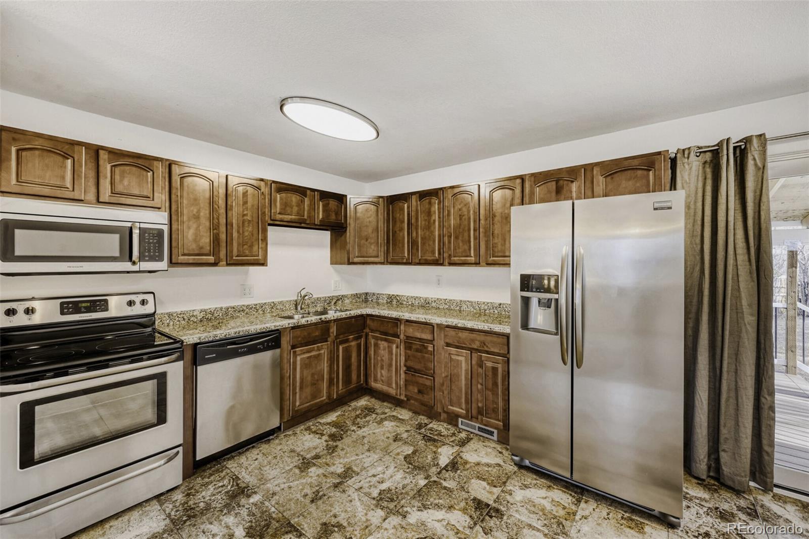 9168 Flower Court Westminster, CO 80021 - Photo 12 of 38 a kitchen with stainless steel appliances granite countertop a refrigerator stove and sink