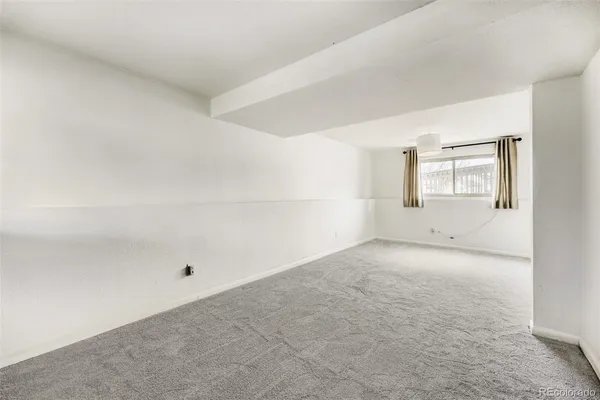 an empty room with windows and refrigerator