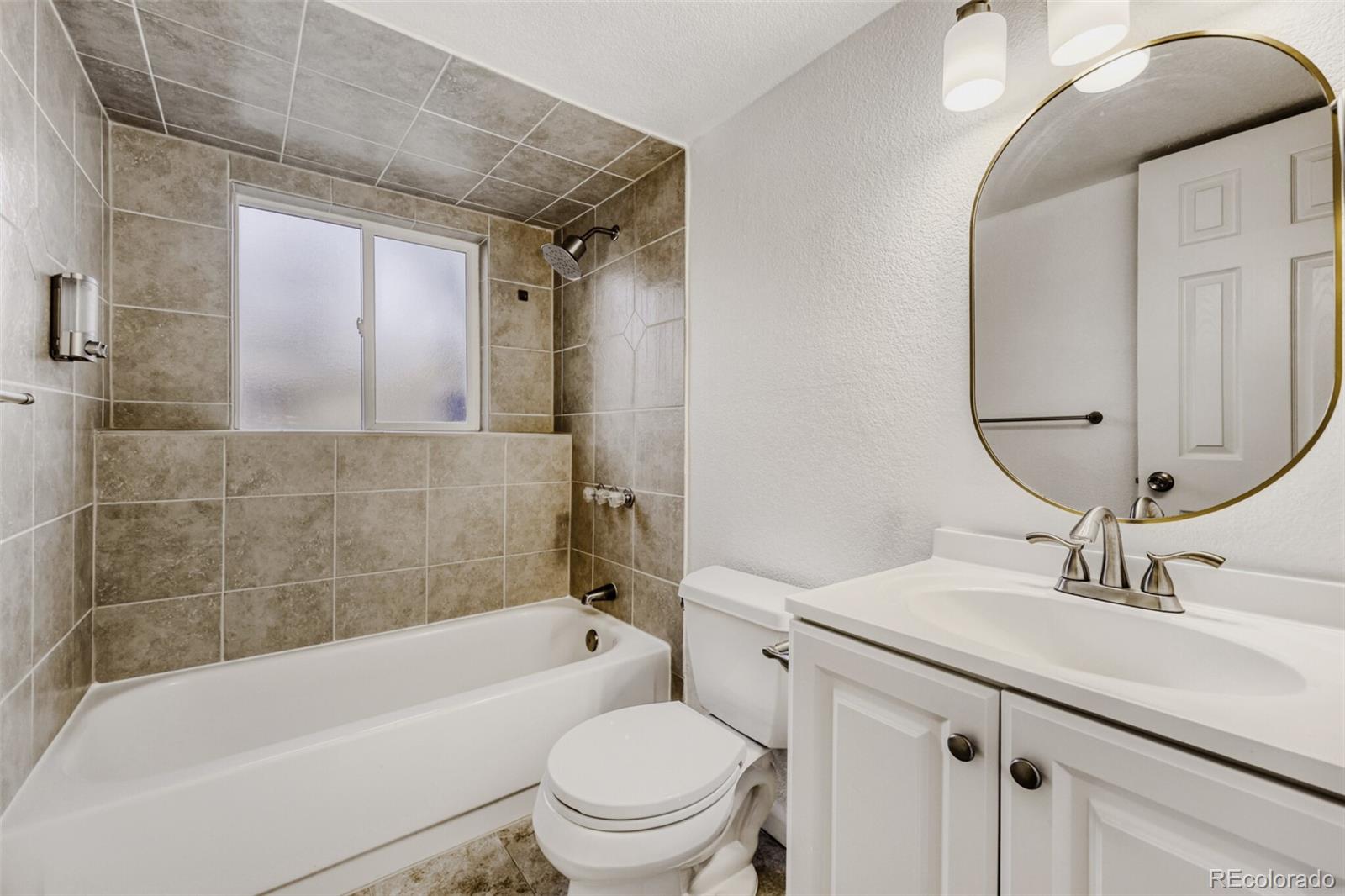 9168 Flower Court Westminster, CO 80021 - Photo 26 of 38 a bathroom with a sink a toilet a mirror and bathtub