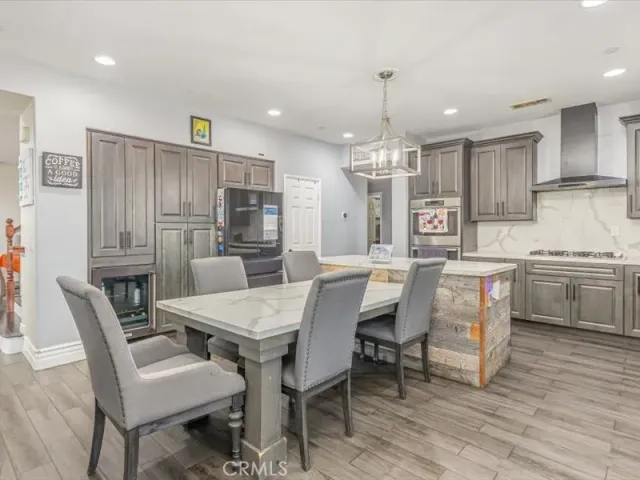 a dining room with stainless steel appliances kitchen island granite countertop a dining table chairs and a refrigerator