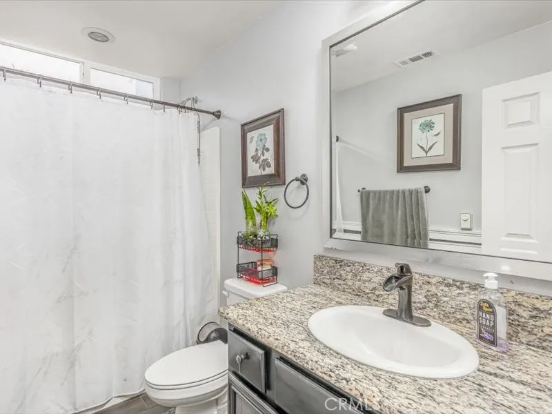 15851 Sulphur Springs Road Moreno Valley, CA 92555 - Photo 21 of 47 a bathroom with a granite countertop sink toilet a mirror and a shower