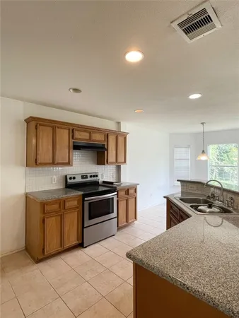 a kitchen with stainless steel appliances granite countertop a stove a sink and a refrigerator