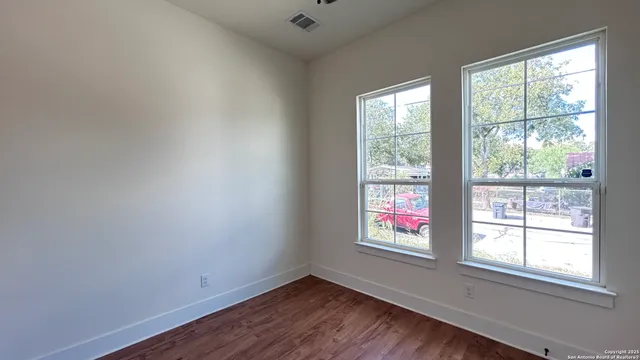 an empty room with wooden floor and windows