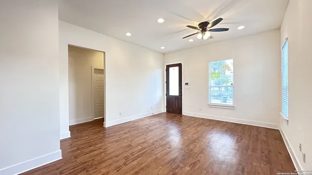 a view of an empty room with wooden floor and a window
