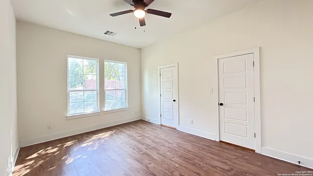 a view of an empty room with a window and wooden floor