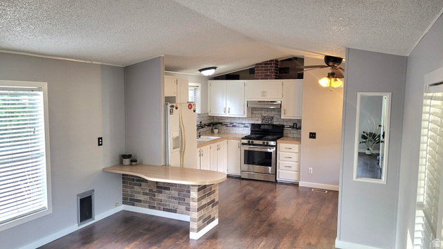 1525 South 400 East, Unit 63 Springville, UT 84663 - Photo 6 of 36 Kitchen featuring light countertops, white cabinetry, stainless steel range with gas cooktop, a textured ceiling, and white refrigerator with ice dispenser