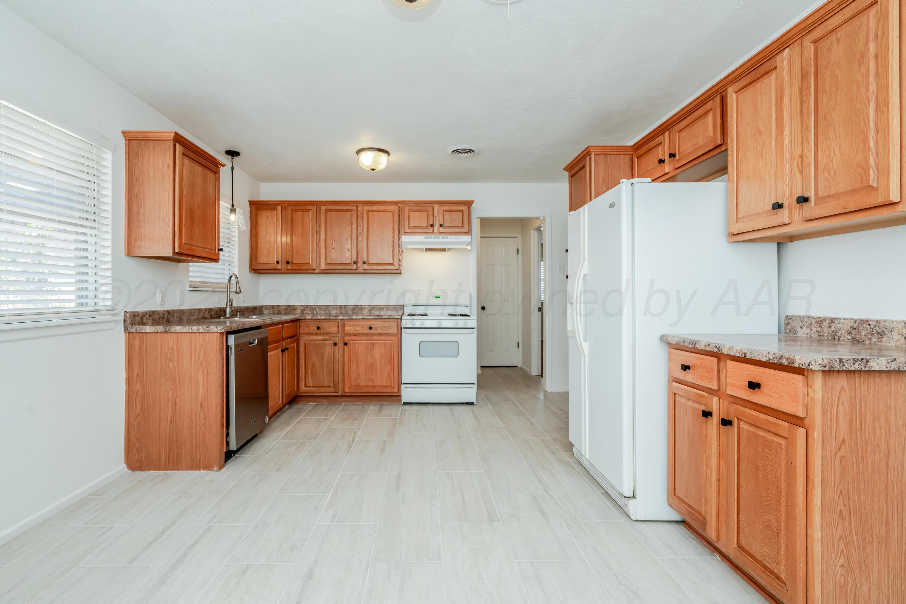 1001 5th Street Canyon, TX 79015 - Photo 4 of 34 a kitchen with stainless steel appliances granite countertop a refrigerator a sink dishwasher and wooden cabinets with wooden floor