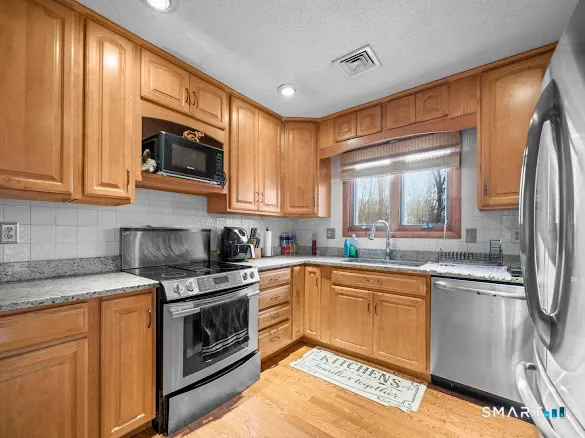 a kitchen with stainless steel appliances granite countertop a stove a sink and a microwave