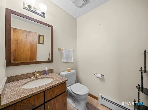 a bathroom with a granite countertop sink vanity mirror and toilet