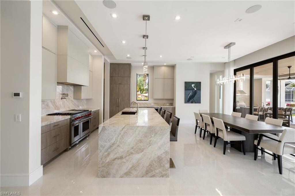 2345 Tarpon Road Naples, FL 34102 - Photo 11 of 43 Two tone kitchen with light stone counters, modern cabinets, two tone cabinets, double oven range, and a large island with sink