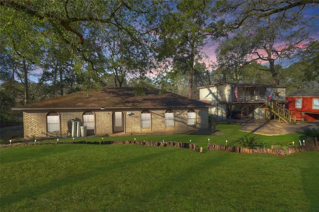 a front view of a house with a garden and trees