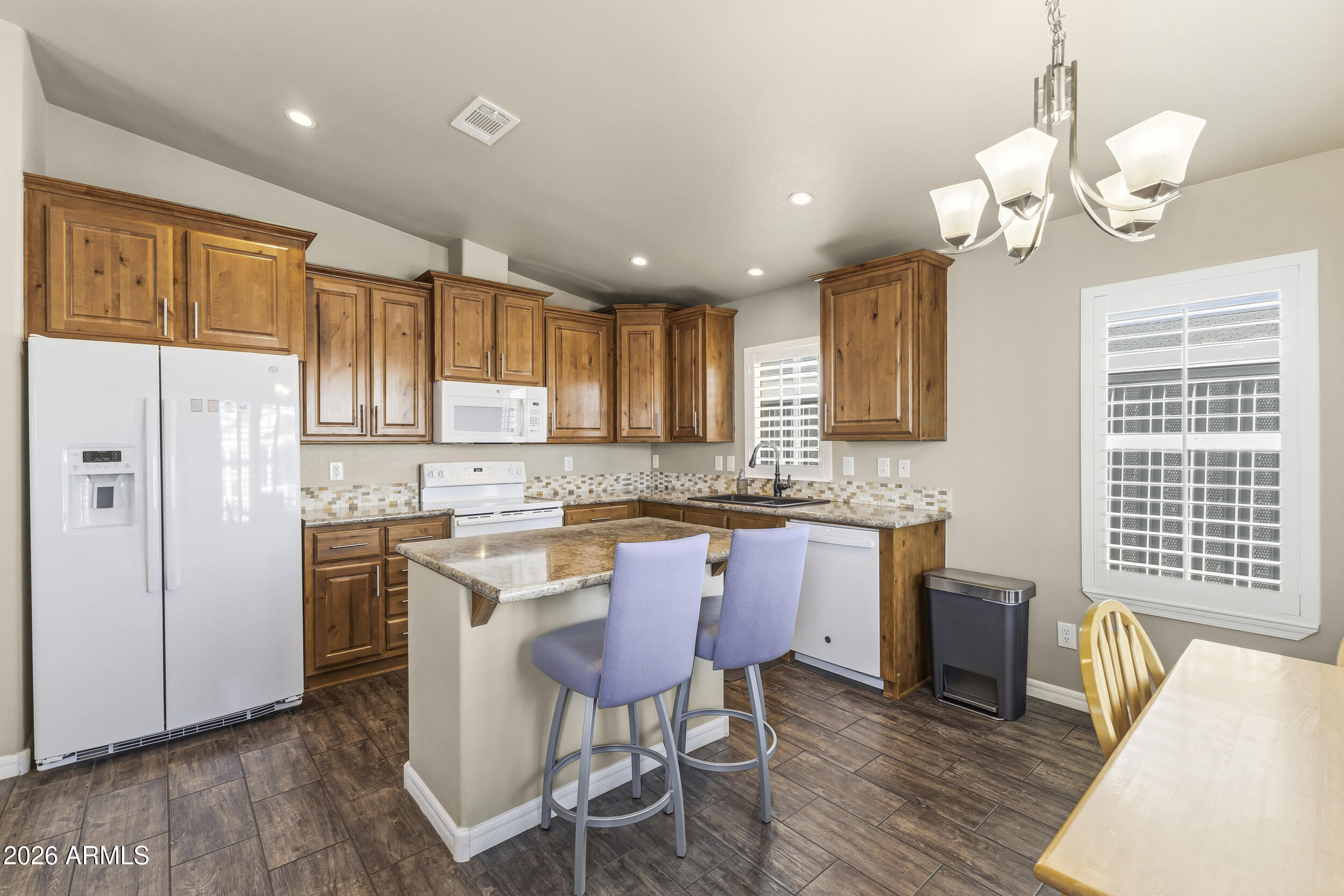 650 North Hawes Road, Unit 3509 Mesa, AZ 85207 - Photo 6 of 43 a kitchen with stainless steel appliances granite countertop a refrigerator a sink dishwasher a dining table and chairs with wooden floor
