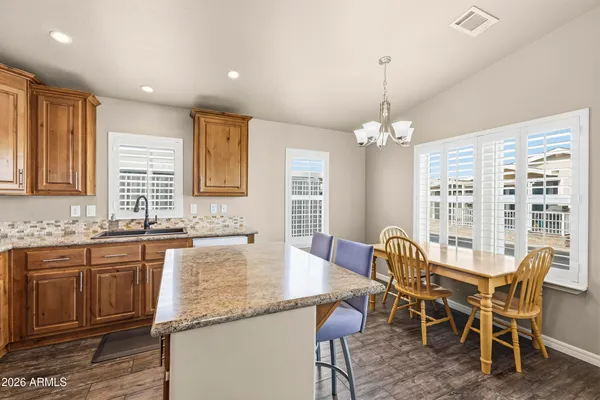 a kitchen with stainless steel appliances granite countertop a refrigerator a sink dishwasher a dining table and chairs with wooden floor