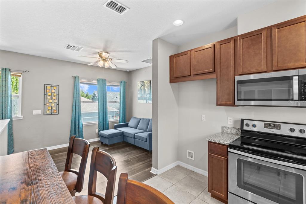 5955 Caldera Ridge Drive Lithia, FL 33547 - Photo 67 of 71 a kitchen with stainless steel appliances granite countertop a stove top oven a sink dishwasher a dining table and chairs with wooden floor