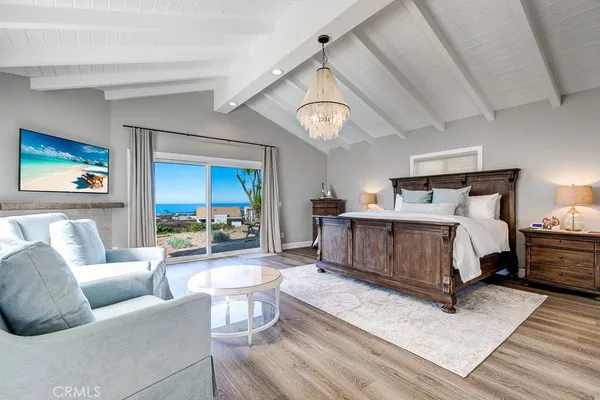 a bedroom with a bed a chandelier and a mirror on the dresser