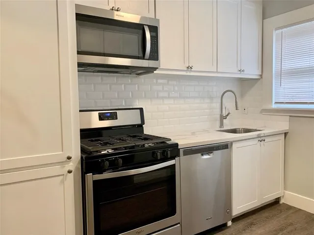 a kitchen with stainless steel appliances granite countertop white cabinets and black stove top oven