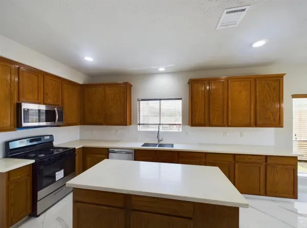 a kitchen with kitchen island granite countertop a sink and a stove top oven with wooden floor