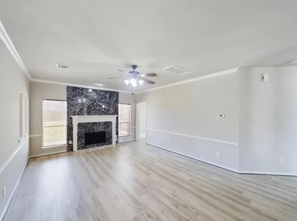 a view of an empty room with wooden floor and a fireplace