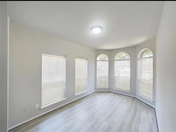an empty room with wooden floor and window