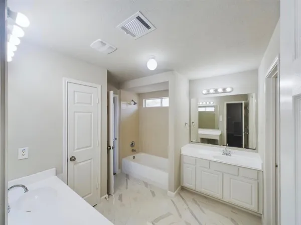 a spacious bathroom with a bathtub shower sink and mirror