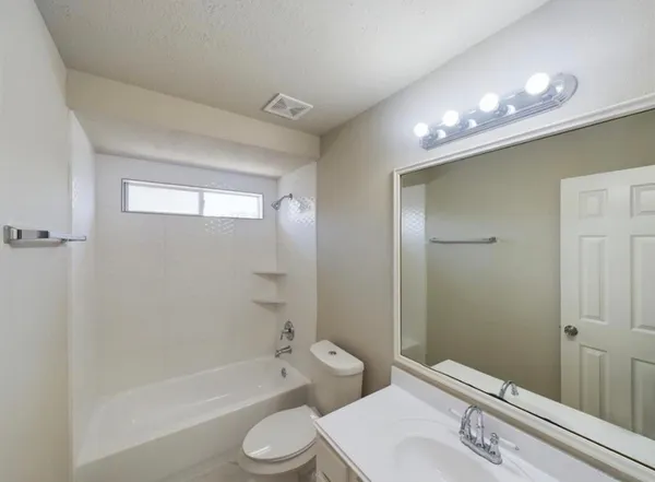 a bathroom with a toilet a sink a mirror a bathtub and shower