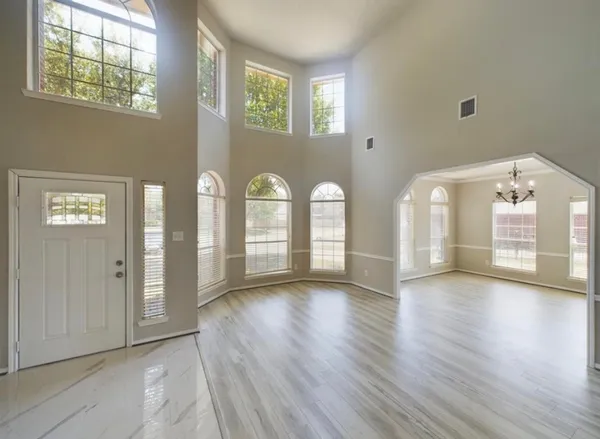a view of an empty room with window and wooden floor