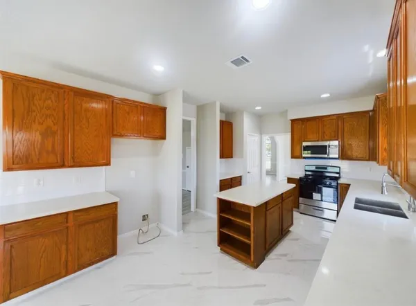 a living room with stainless steel appliances kitchen island granite countertop a refrigerator and cabinets