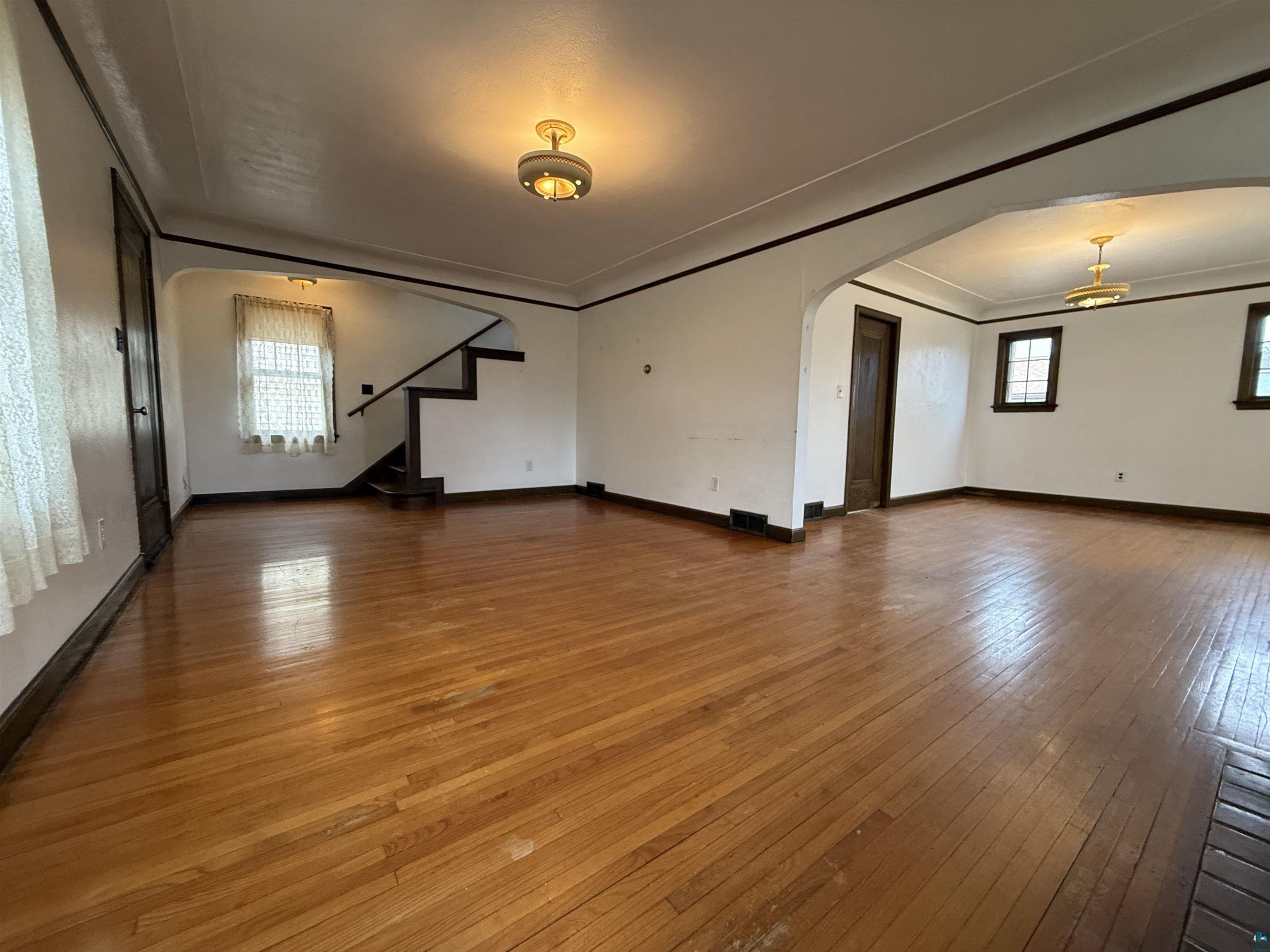 3001 3rd Avenue West Hibbing, MN 55746 - Photo 9 of 38 Unfurnished living room featuring dark wood-style floors, arched walkways, and ornamental molding