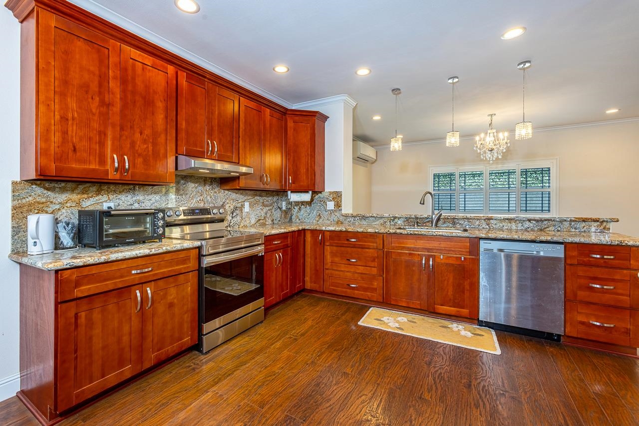 a large kitchen with stainless steel appliances granite countertop wooden floors wooden cabinets a sink and a stove