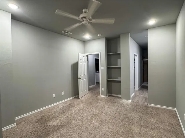 an empty room with closet and a ceiling fan