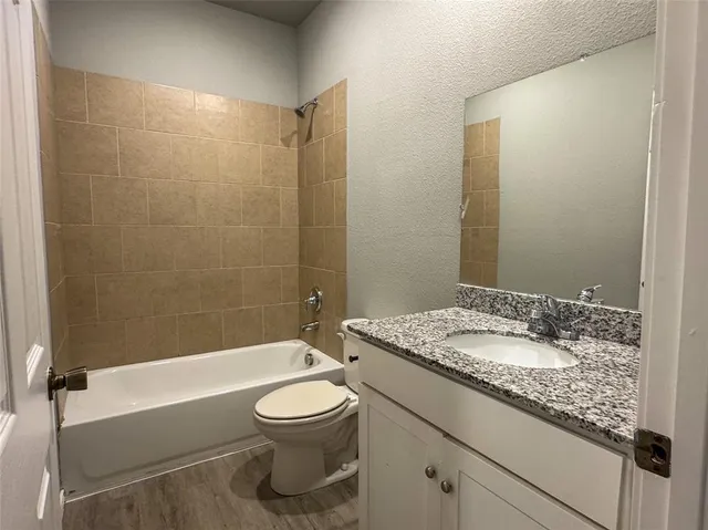 a bathroom with a granite countertop sink a toilet and bathtub