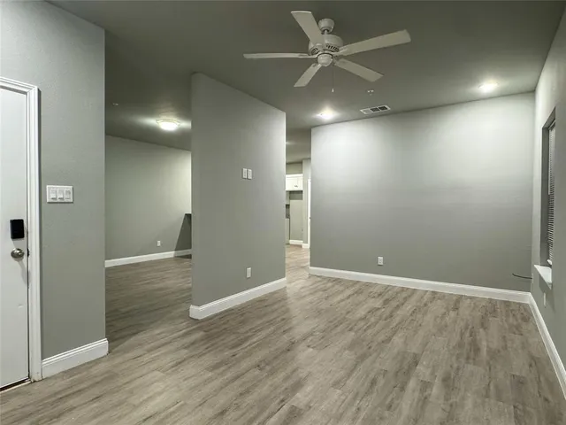 an empty room with wooden floor and fan