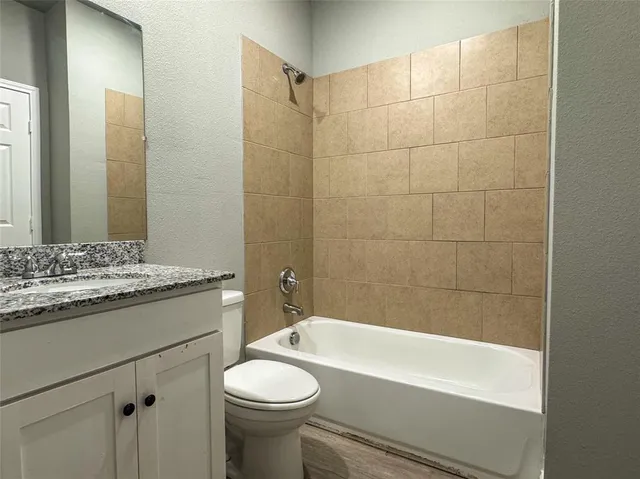 a bathroom with a granite countertop sink a toilet mirror and bathtub