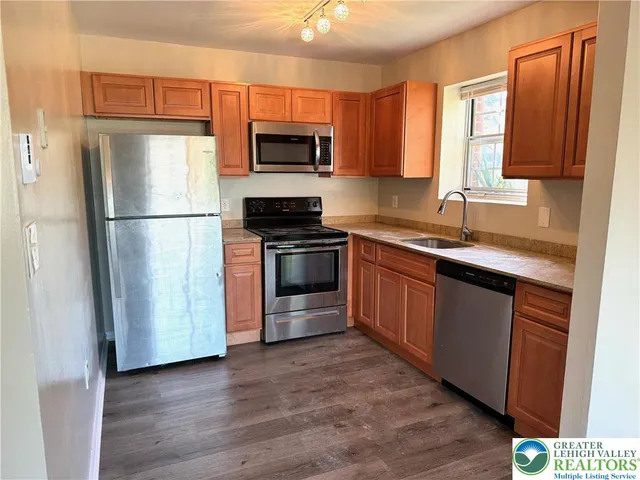 a kitchen with stainless steel appliances granite countertop a refrigerator stove a sink and dishwasher with wooden floor