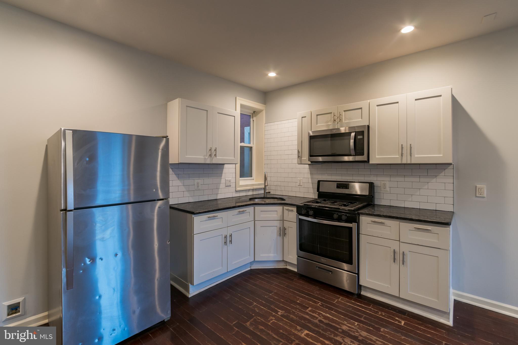 723 South 56th Street, Unit 1 Philadelphia, PA 19143 - Photo 3 of 18 a kitchen with kitchen island a sink stainless steel appliances and cabinets