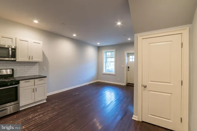 a view of a kitchen with a sink stove cabinets and empty room