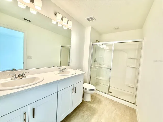 a bathroom with a double vanity sink toilet and shower