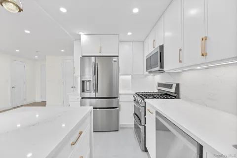 a kitchen with a sink stainless steel appliances and white cabinets
