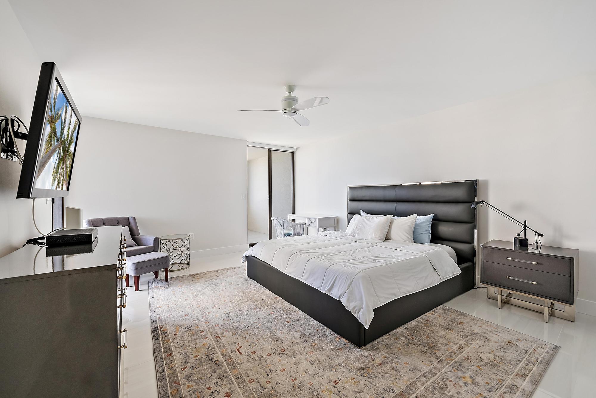 5070 North Ocean Drive, Unit 5B Riviera Beach, FL 33404 - Photo 9 of 37 a bedroom with a bed and flat screen tv