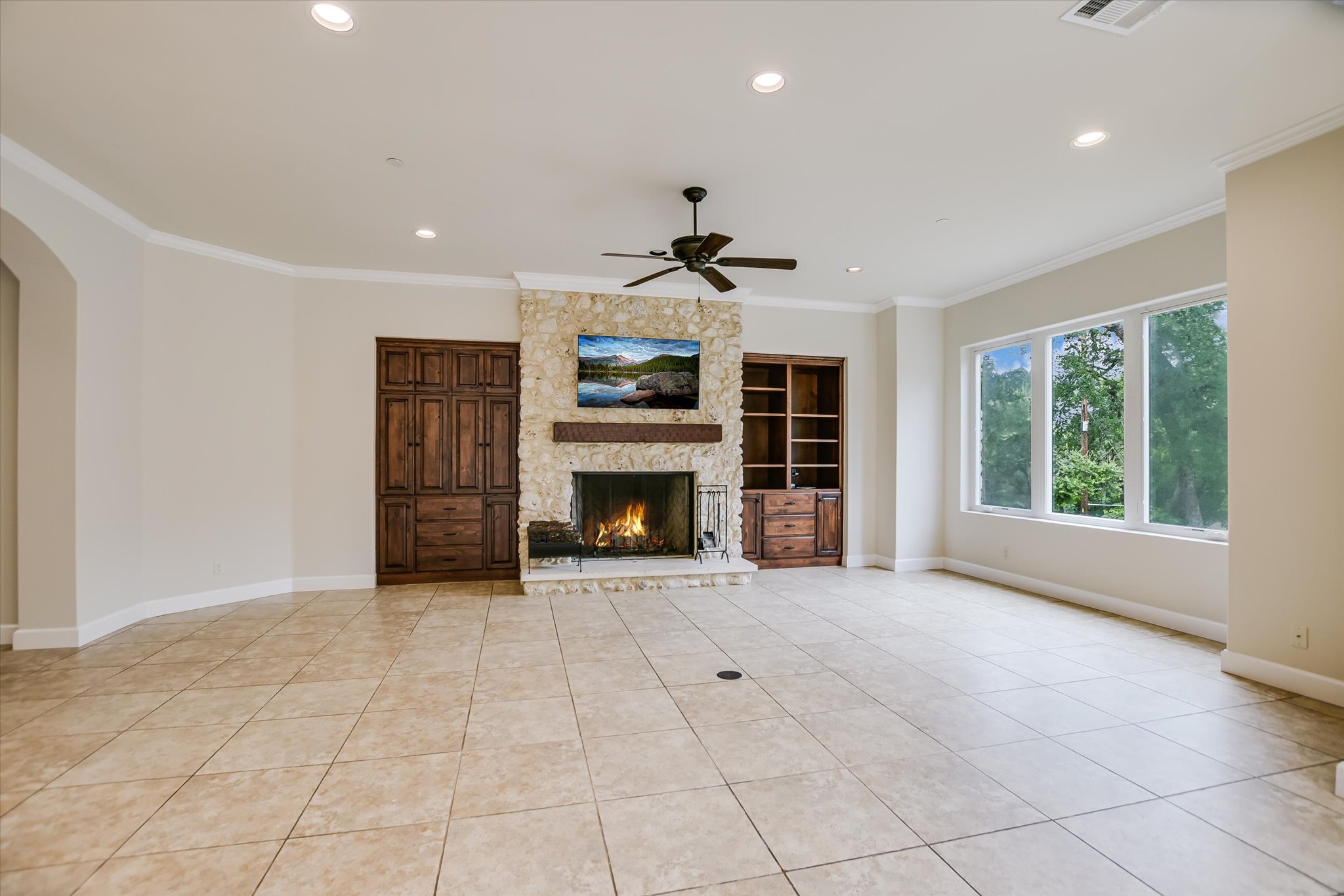 11 Inwood Circle Austin, TX 78746 - Photo 11 of 38 A spacious living area showcases a captivating stone fireplace, built-in cabinetry, and abundant natural light from large windows.