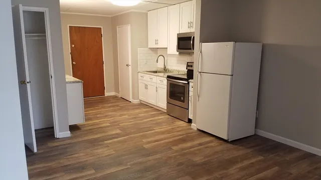 a kitchen with a refrigerator a stove top oven and cabinets