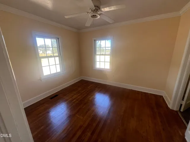 a view of an empty room with wooden floor and a window